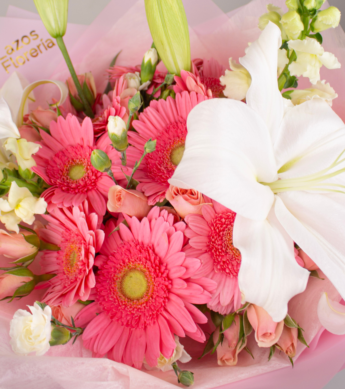Ramo de 10 gerberas rosadas con lirio blanco y dogos en envoltura rosa pastel para regalo de cumpleaños en Lima de Florería Lazos.