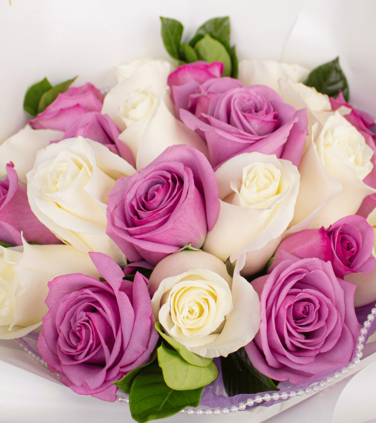 Ramo de rosas moradas y blancas con detalle de perlas en envoltura blanca para regalo de cumpleaños en Lima de Florería Lazos.