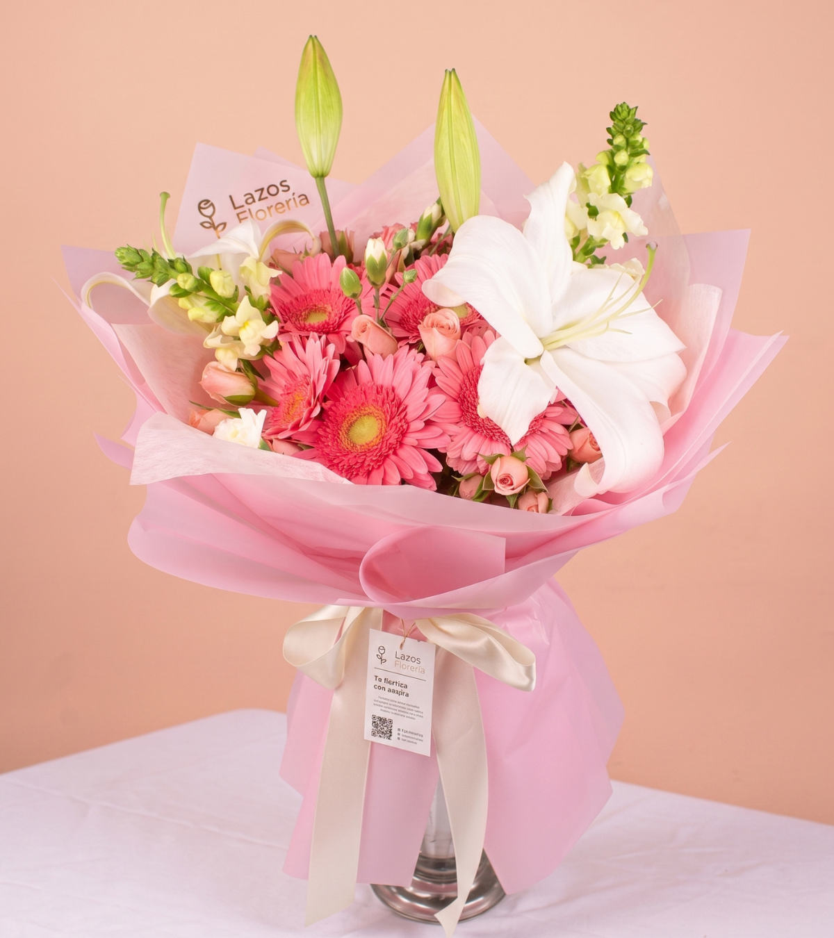 Ramo de 10 gerberas rosadas con lirio blanco y dogos en envoltura rosa pastel para regalo de cumpleaños en Lima de Florería Lazos.