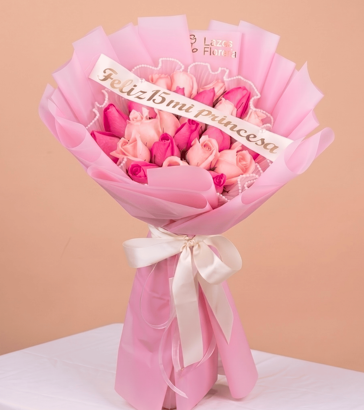 Arreglo de rosas en tonos rosados con banda de feliz quince años ideal para obsequio de quinceañera con delivery en Lima.